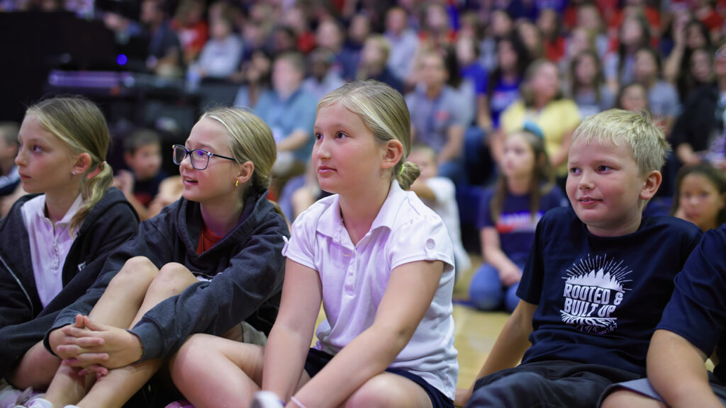 Children sitting in a gym at school.