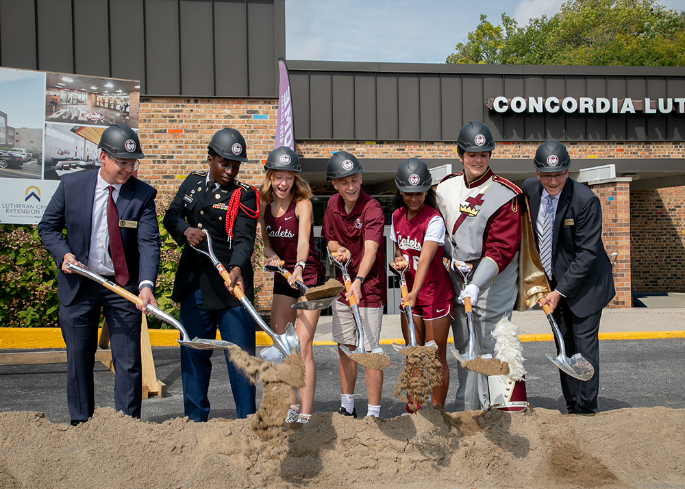 A group of faculty, staff and students at Concordia Lutheran High School perform the ceremonial first dig of the school's construction site.