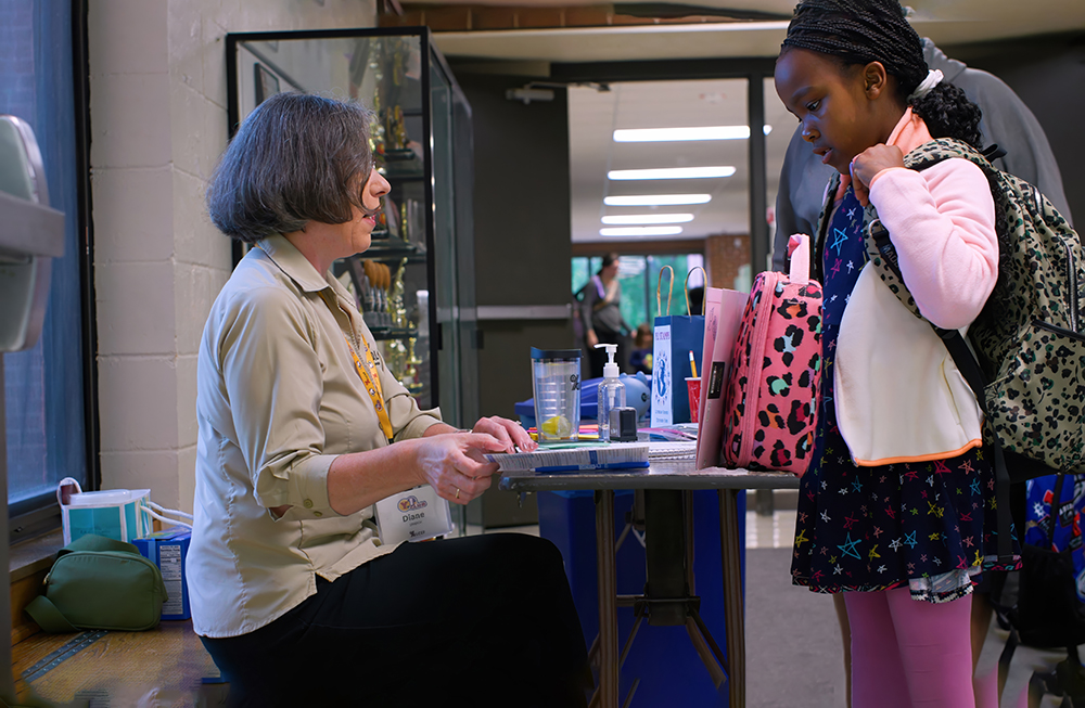 Diane Streich assists a child with her Young Investors StewardAccount.
